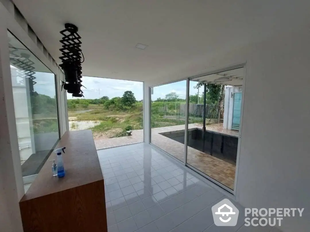 Spacious and modern living area with large sliding glass doors opening to a serene outdoor view, featuring sleek tile flooring and ample natural light.