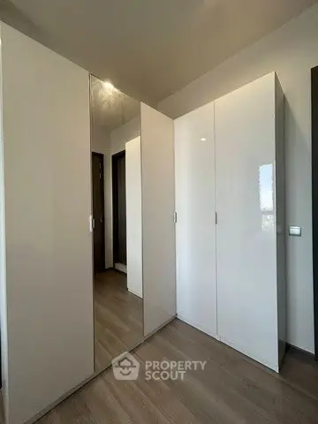 Spacious modern storage area with sleek white cabinets and wooden flooring.