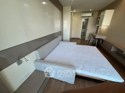Modern bedroom with foldable bed and sleek workspace in a stylish apartment.