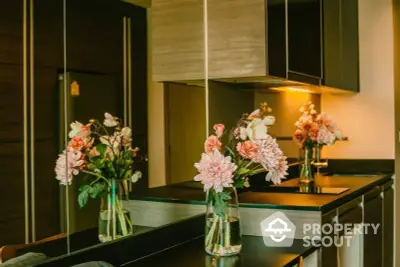 Elegant kitchen interior with modern cabinetry and pendant lighting, featuring a sleek countertop adorned with fresh flowers.