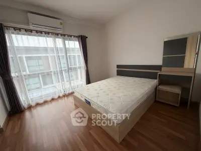 Spacious bedroom with large window and modern furnishings in a stylish apartment.