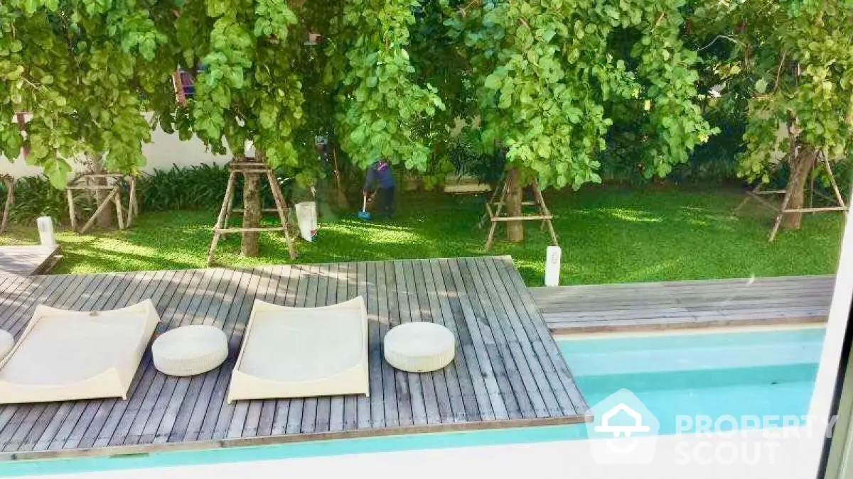 Luxurious outdoor pool area with wooden deck and lush green garden view