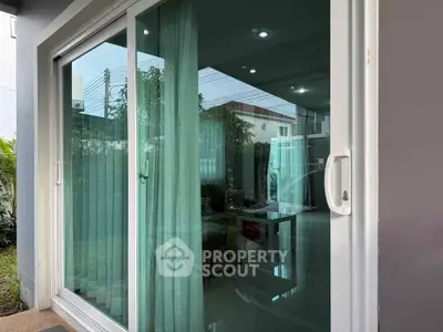 Modern sliding glass door leading to a stylish living room with lush garden view.
