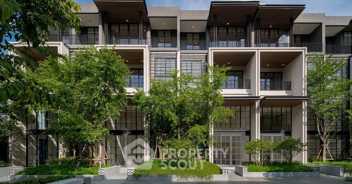 Modern multi-story building with lush greenery and large windows, showcasing contemporary architectural design.