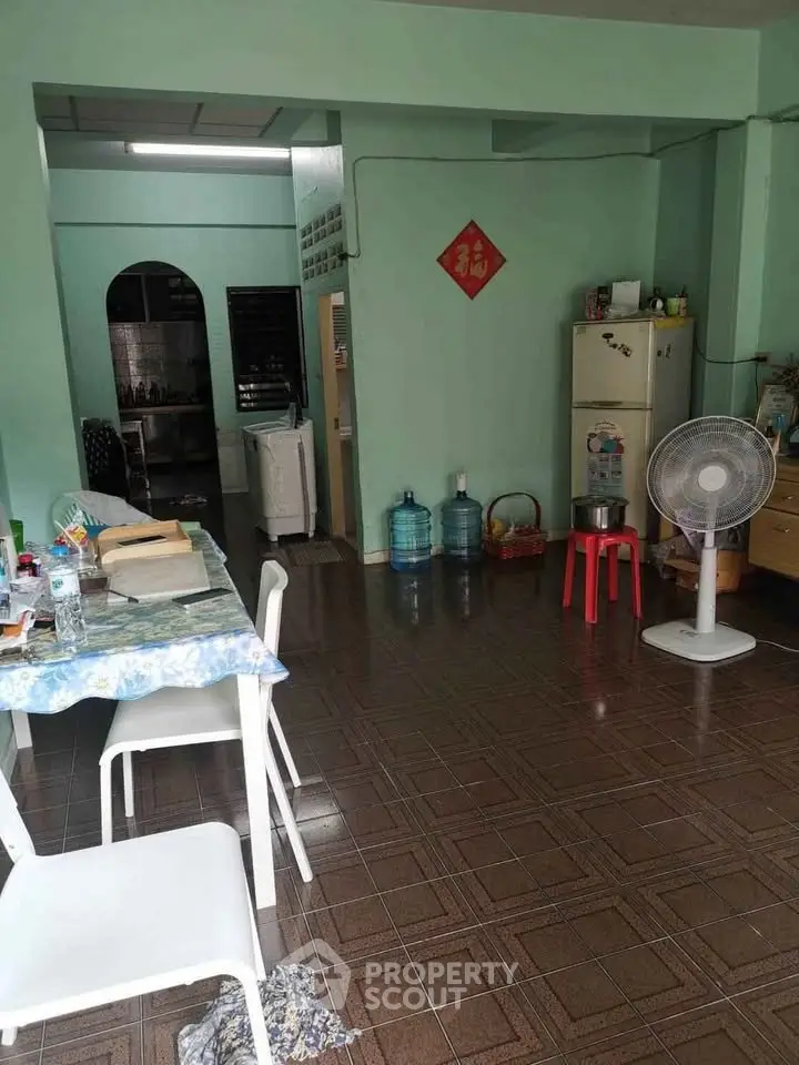 Cozy living space with dining area, fan, and kitchen access, featuring tiled flooring and practical furnishings.