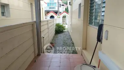 Charming exterior walkway with tiled entrance and gravel path leading to a cozy residential area.