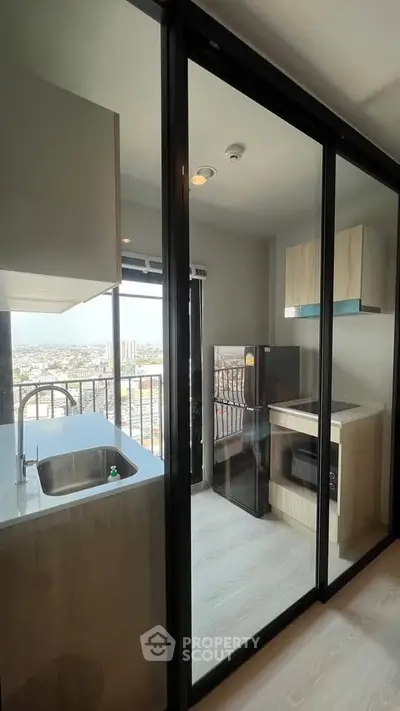 Modern kitchen with glass partition and city view, featuring sleek appliances and stylish cabinetry.