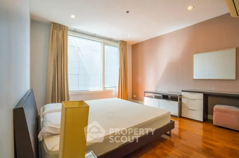 Spacious bedroom with large window and modern furnishings in a bright apartment.
