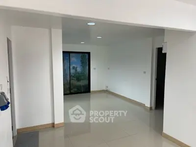 Spacious empty room with large window and tiled flooring, perfect for customization.