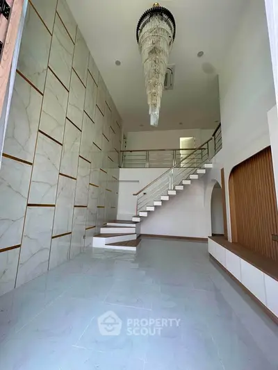 Luxurious modern interior with high ceiling and elegant chandelier in spacious living area.