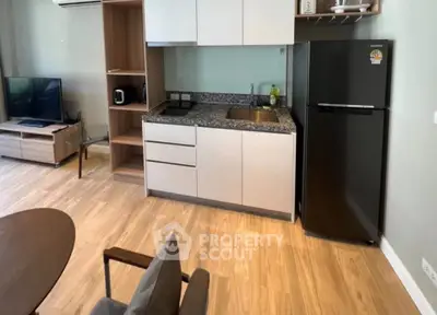 Modern apartment kitchen with sleek cabinetry and appliances, featuring a compact open layout.