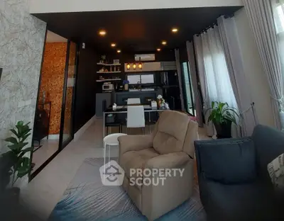 Modern living room with open kitchen, stylish decor, and cozy seating area.