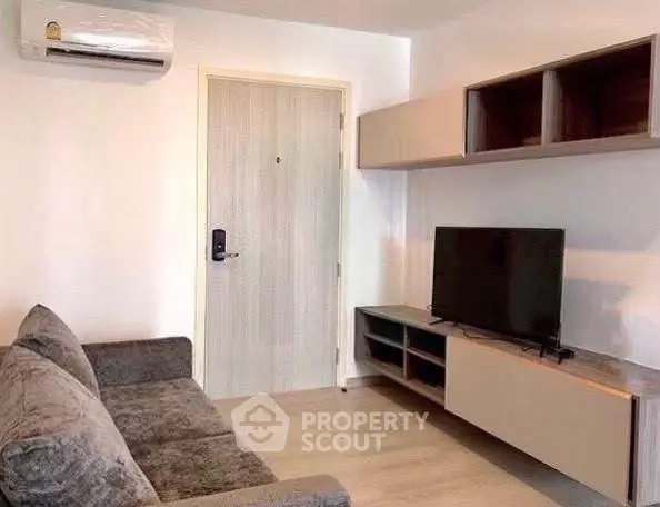 Modern living room with sleek furniture and wall-mounted TV, featuring air conditioning and stylish shelving.