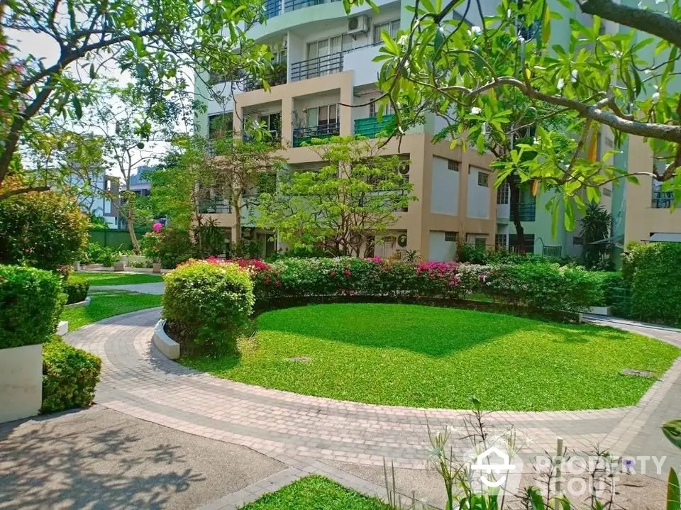 Beautiful garden view in modern residential complex with lush greenery and well-maintained pathways.