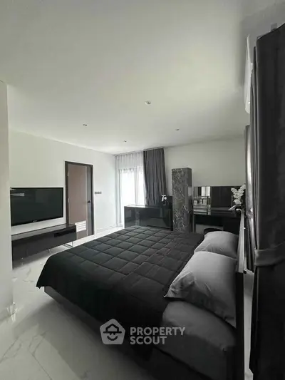 Modern bedroom with sleek black decor and large TV, perfect for luxury living.