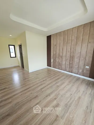 Spacious empty room with elegant wood flooring and modern wall paneling
