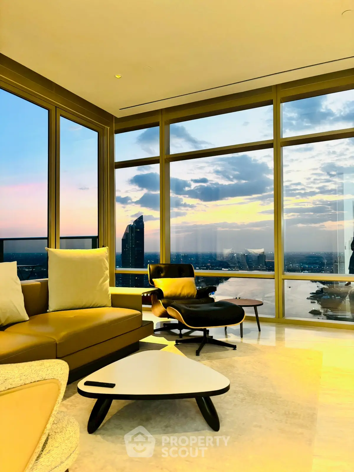 Luxurious living room with panoramic city view and modern furniture at sunset.
