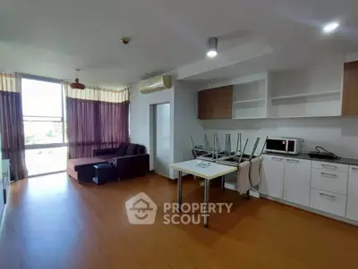 Spacious living room with modern kitchen in open layout, featuring large windows and stylish furniture.