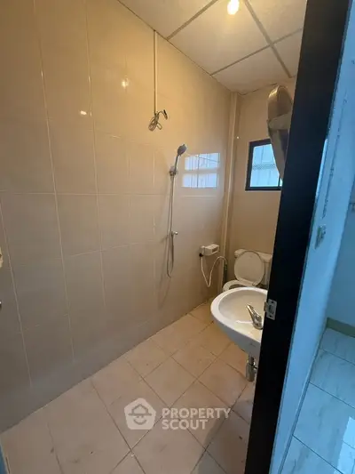Compact bathroom with shower and toilet in a tiled interior space.