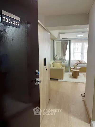 Modern apartment entrance leading to cozy living room with natural light and stylish decor.