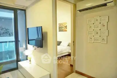 Modern apartment interior with wall-mounted TV and air conditioning, leading to a cozy bedroom.