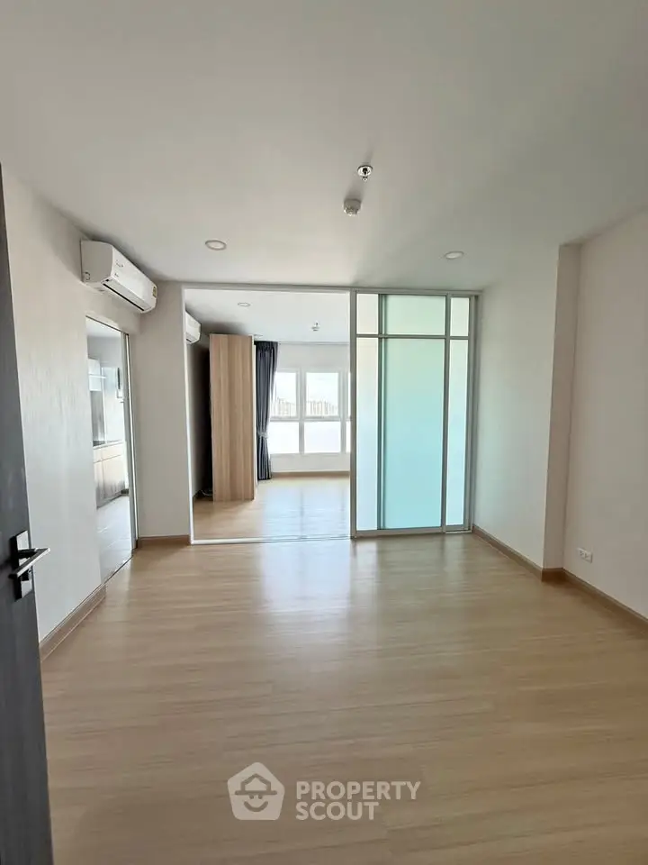 Spacious modern living room with wooden flooring and large windows for natural light.