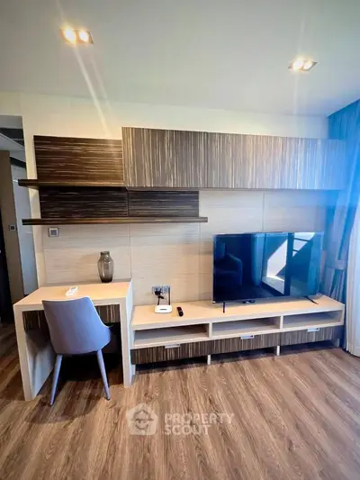 Modern living room with stylish TV unit and workspace, featuring wooden flooring and contemporary decor.