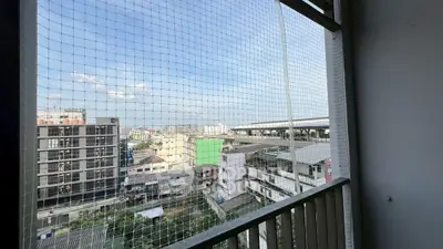 Urban apartment balcony with cityscape view and protective netting.