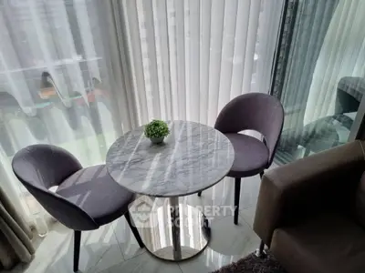 Modern apartment corner with marble table and elegant chairs by large windows.