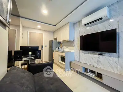 Modern living room with sleek kitchen and large TV, featuring stylish decor and air conditioning.