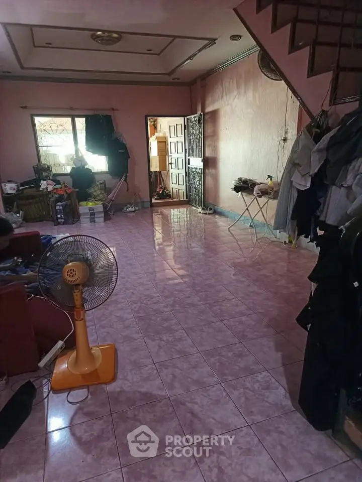 Spacious living room with tiled flooring and staircase, ideal for family gatherings.