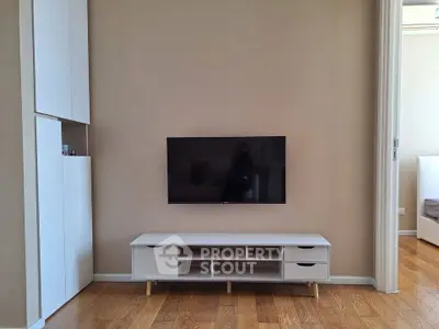 Modern living room with sleek TV stand and mounted flat-screen TV, showcasing minimalist design and wooden flooring.