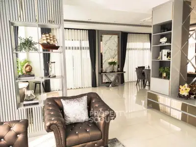 Luxurious living room with elegant decor and plush leather seating, featuring floor-to-ceiling windows and stylish shelving.