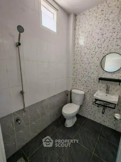 Modern bathroom with sleek design, featuring a shower, toilet, and stylish wall tiles.