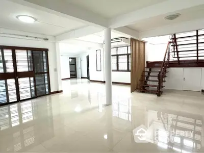 Spacious open-plan living area with modern staircase and large windows