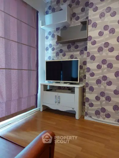 Charming living room with modern decor and flat-screen TV, featuring stylish wallpaper and wooden flooring.