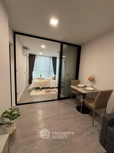 Modern studio apartment with glass partition, cozy dining area, and stylish decor.