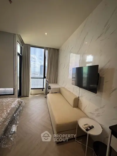 Modern living room with sleek design, featuring a wall-mounted TV, cozy sofa, and large window with city view.