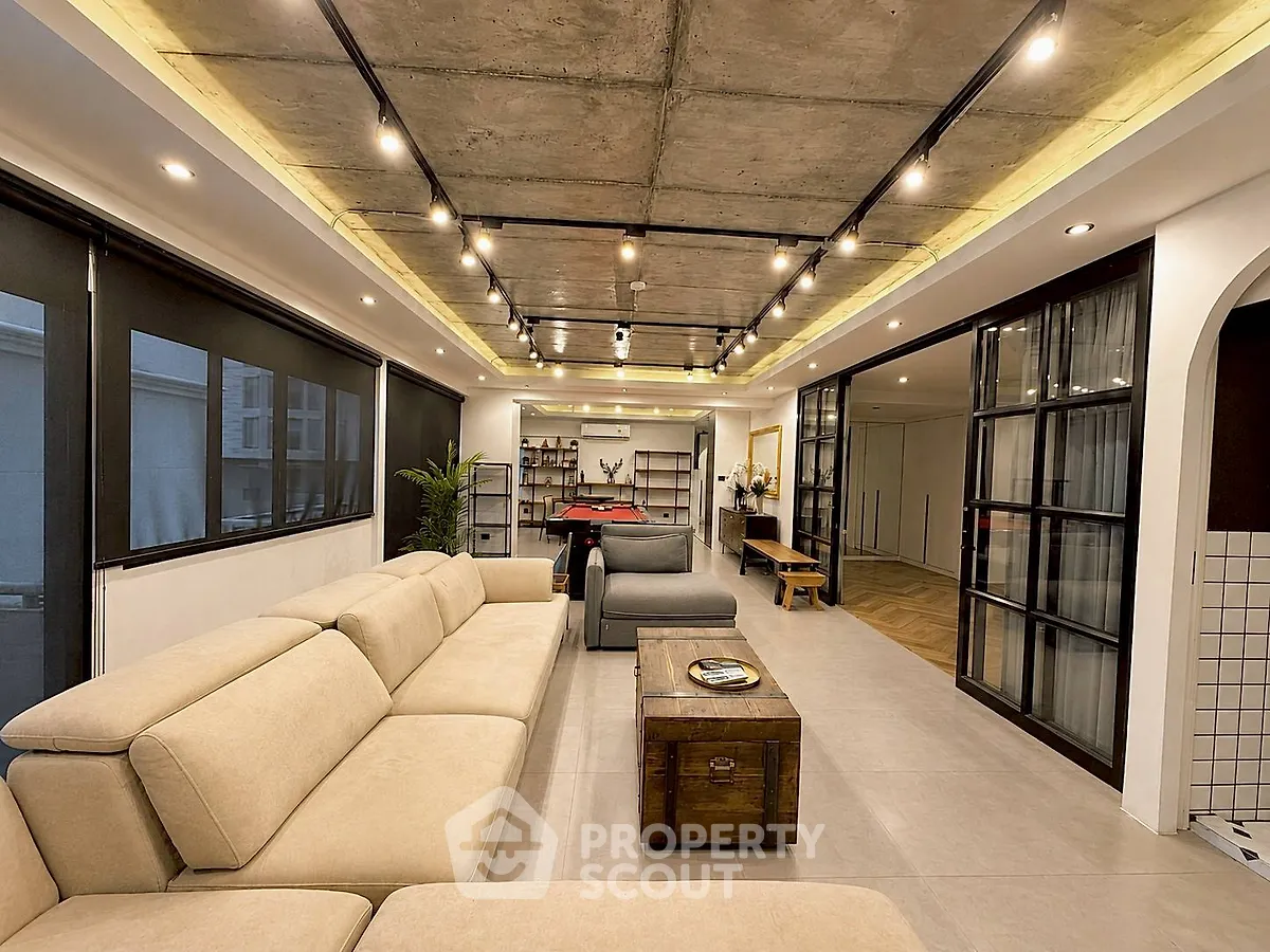 Spacious modern living room with industrial ceiling and cozy beige sofa