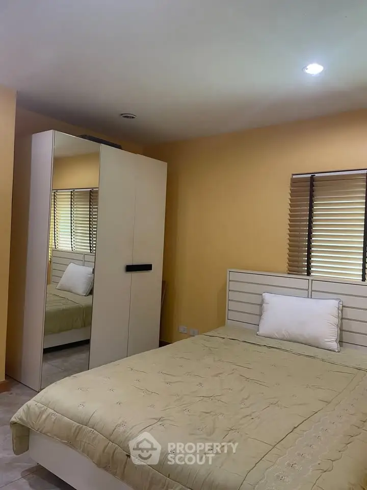 Cozy bedroom with mirrored wardrobe and soft lighting, perfect for relaxation.