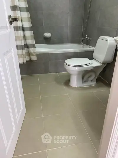 Modern bathroom with bathtub and neutral tiles, perfect for relaxation.