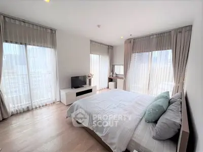 Spacious bedroom with large windows and modern decor, perfect for relaxation and comfort.