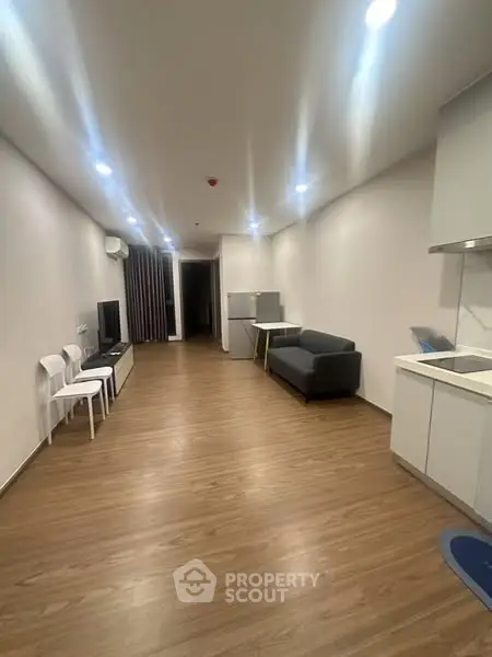 Spacious modern living room with sleek wooden flooring and minimalist furniture.