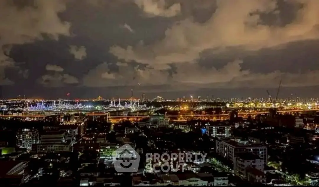 Stunning cityscape view at night with illuminated skyline and dramatic clouds.
