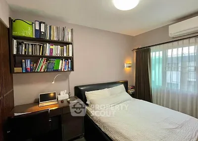 Cozy bedroom with study area, featuring a comfortable bed, desk, and ample shelving for books and storage.