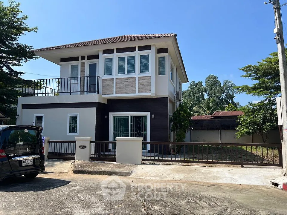 Modern two-story house with balcony and spacious driveway in serene neighborhood.