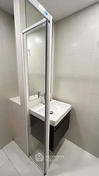 Modern bathroom with sleek sink and large mirror in a compact space.