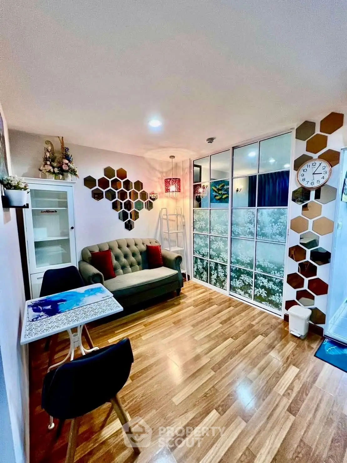 Charming living room with stylish decor and wooden flooring, featuring a cozy sofa and modern wall accents.