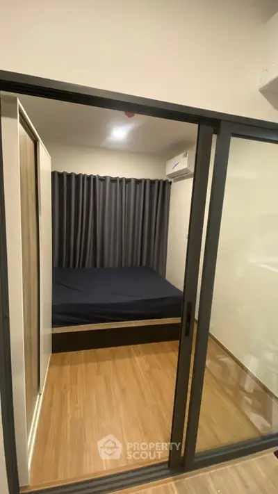 Modern compact bedroom with sliding glass doors and wooden flooring
