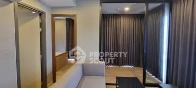 Modern living room with sleek design and floor-to-ceiling curtains, featuring a cozy sofa and wooden flooring.